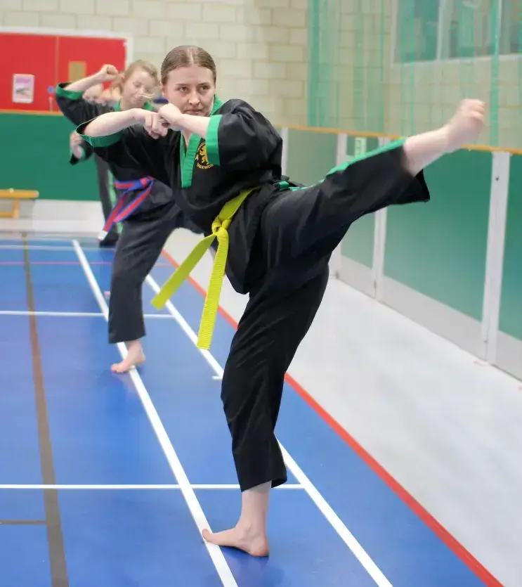 A yellow belt does a high kick